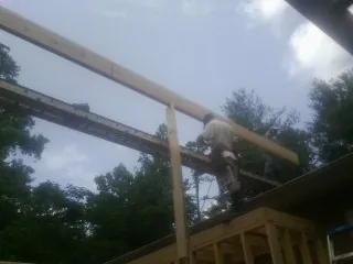 Carpenter setting a ridge beam over a new addition frame — Ice Dam Removal by Roofing Brothers in Victor